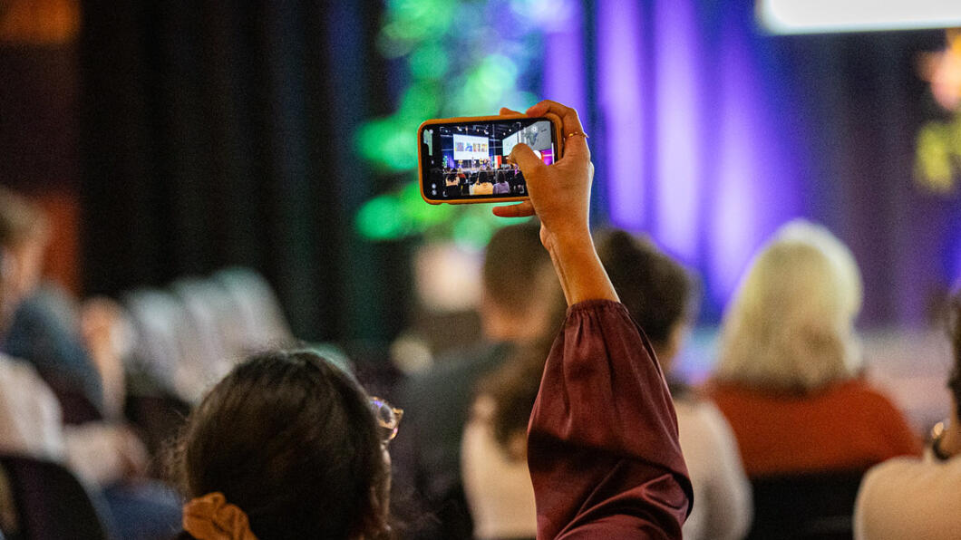 persoon houdt telefoon omhoog om een foto te maken in een zaal